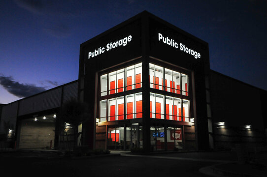 Public Storage building with illuminated signage and red storage unit doors is seen at night, highlighting self-storage services in a secure, multi-level commercial facility
