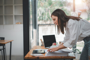 Businesswoman working in Stacks of paper files for searching and checking unfinished document...