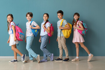 Obraz premium Little pupils with backpacks near blue wall