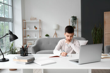 Little boy studying online with laptop at home