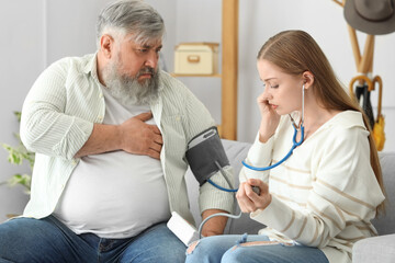 Fototapeta premium Young woman measuring blood pressure of her father with heart attack at home