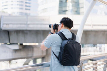 Young traveler man with Camera taking picture from view point. Asian man tourist traveler travel alone on street use Camera record vlog. Travel concept.