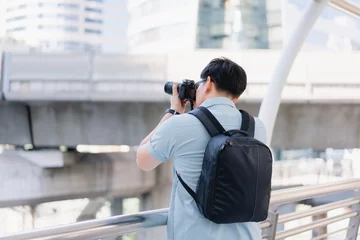 Deurstickers Young traveler man with Camera taking picture from view point. Asian man tourist traveler travel alone on street use Camera record vlog. Travel concept. © Exnoi