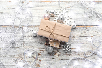 Christmas lights, gift box and decor on white wooden background