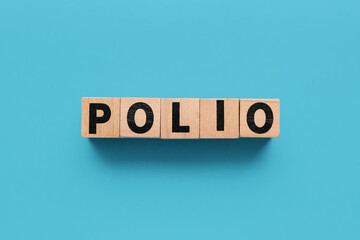 Word POLIO made of wooden cubes on blue background