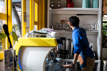Fototapeta na wymiar An Asian barista preparing coffee to customers at a coffee shop.
