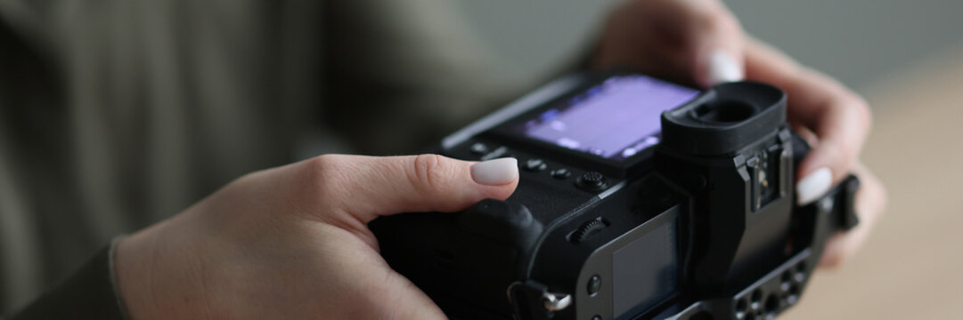 Hands of woman holding professional camera with small screen
