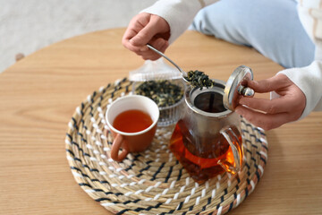 Young woman brewing tea at home, closeup