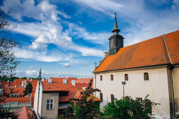 Obraz premium Petrovaradin is historic town on right bank of Danube in Serbia, part of Novi Sad. Top view of the tiled orange roofs with white chimneys and magic cloudy sky