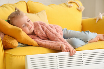 Obraz na płótnie Canvas Cute little girl with radiator lying on sofa at home