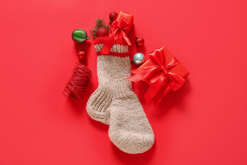 Christmas sock with balls and gift boxes on red background