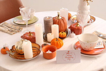 Festive table setting with burning candles, pumpkins and greeting cards for Thanksgiving Day