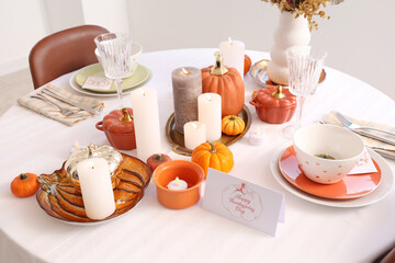 Festive table setting with burning candles, pumpkins and greeting cards for Thanksgiving Day