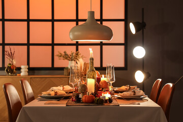 Festive table setting with burning candles, pumpkins and greeting cards for Thanksgiving Day at evening