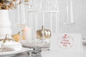 Greeting card with text HAPPY THANKSGIVING DAY on dining table, closeup