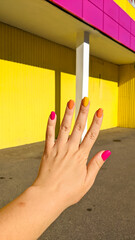 Bright colorful nails of woman hand in yellow, pink and orange colors outdoor