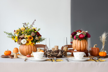 Festive table setting with bouquets of autumn flowers in pumpkins