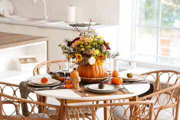 Pumpkin with autumn bouquet on dining table in kitchen