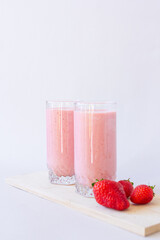 Strawberry fresh pink berry smoothie in two glasses on white