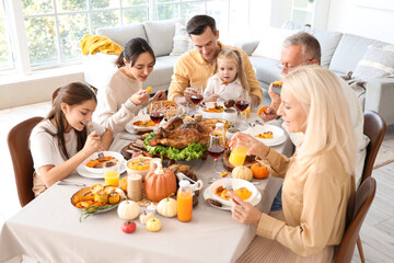 Happy family having dinner at festive table on Thanksgiving Day