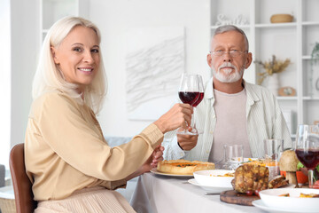 Mature couple having dinner at festive table on Thanksgiving Day