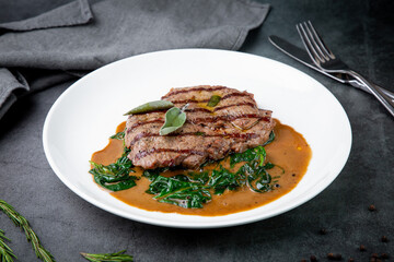 beef steak with gravy and herbs on a white plate