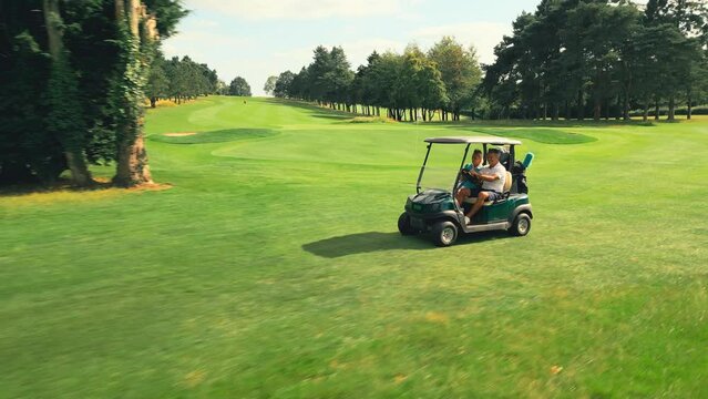 Drone shot of senior retired couple riding in golf buggy on course- shot in slow motion