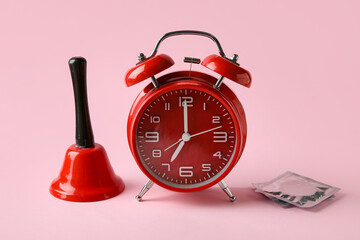 Alarm clock with bell and condoms on pink background. Time for sex