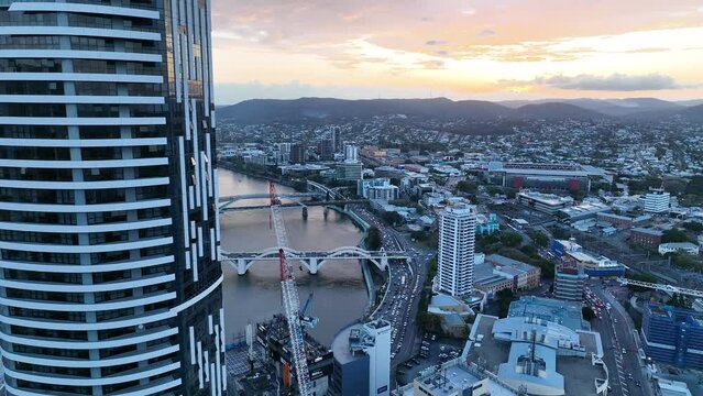 Aerial shot flying above Brisbane CBD, pull away revealing Brisbane Skyscraper the Meriton Building. Shot reveals Brisbane River and skyscraper. Shot at golden hour sunset.