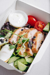 pieces of chicken with vegetables, herbs and sauce in a lunchbox