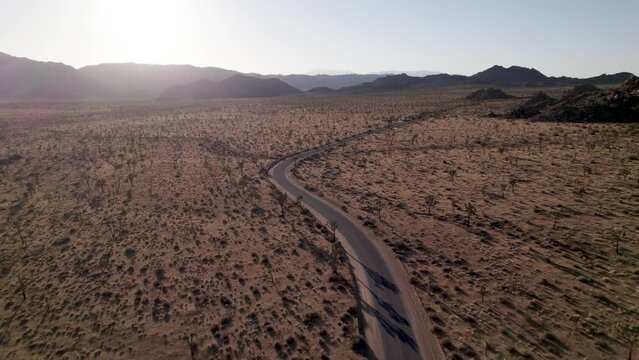 drone flying into sunset over empty road in joshua tree california