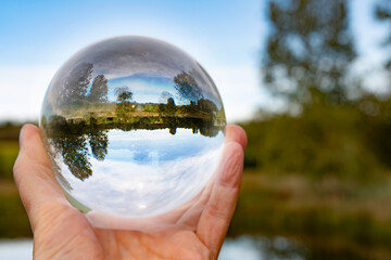 Focus on taking care of nature shown with a glass ball  reflecting the Scandinavian forests, landscapes and nature inside and outside the ball. A room with nature in the nature.