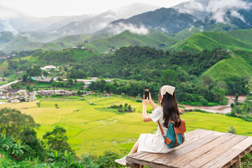 Fototapeta na wymiar Young happy woman tourist enjoying and relaxing with beautiful landscape view rice paddy field while traveling at Nan, Thailand
