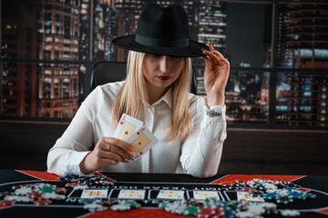 female player showing two aces and gambling chips in poker game at casino table