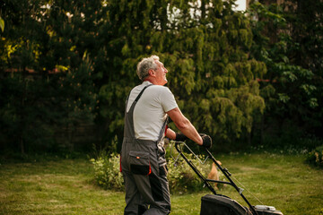 Experienced senior gardener keeps his lawn immaculate while wearing a classic suit
