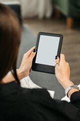 Young woman sitting the couch with an e-book