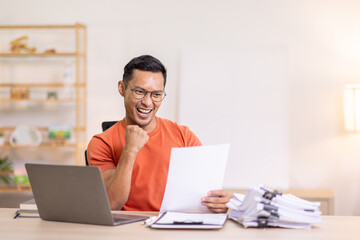 Excited Asian man sit at desk feel euphoric win online lottery, happy asian man overjoyed get mail at laptop being promoted at work, biracial man good news at computer
