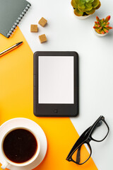 E-book reader with coffee cup and glasses on white and yellow background