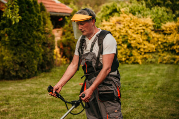 Senior man, equipped in safety gear, skillfully using a grass trimmer to maintain his lush green lawn in his retirement oasis