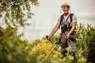 A seasoned gardener, dressed in a protective work suit, meticulously trimming the edges of his...