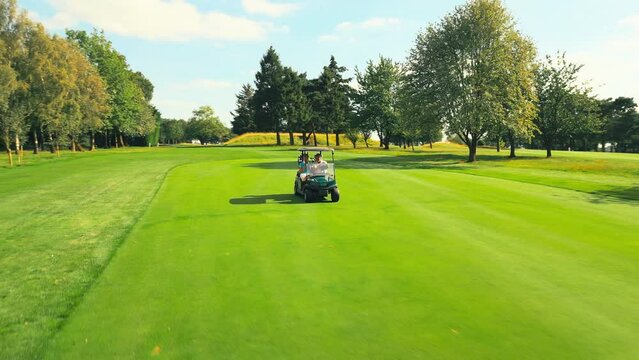Drone shot of senior retired couple riding in golf buggy on course- shot in slow motion