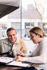 woman and man working together while having coffee on a terrace in the financial district, concept of business and urban lifestyle, copy space for text