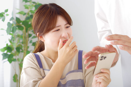 男性のスマホを見て複雑な表情をする女性