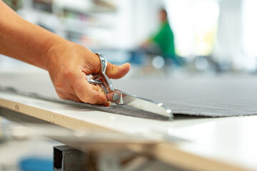 Seamstress cutting fabric with scissors at table close up
