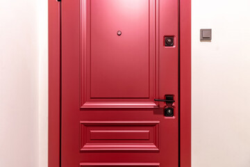 The close up image of a newly installed front door on a home. The door is a deep red, berry color