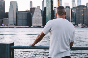 Young man standing with near metallic fence and river