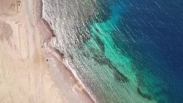 Aerial birdseye descending over deserted beach with turquoise waters, Tabuk