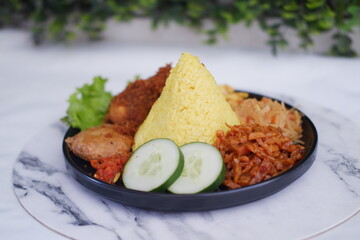 indonesian style yellow rice with chicken and side dishes in black plate