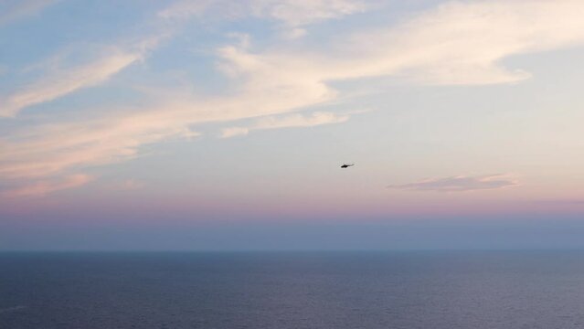 Aerial view of helicopter flying over sea. Image of military helicopter flying