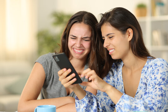 Disgusted women checking cell phone content at home
